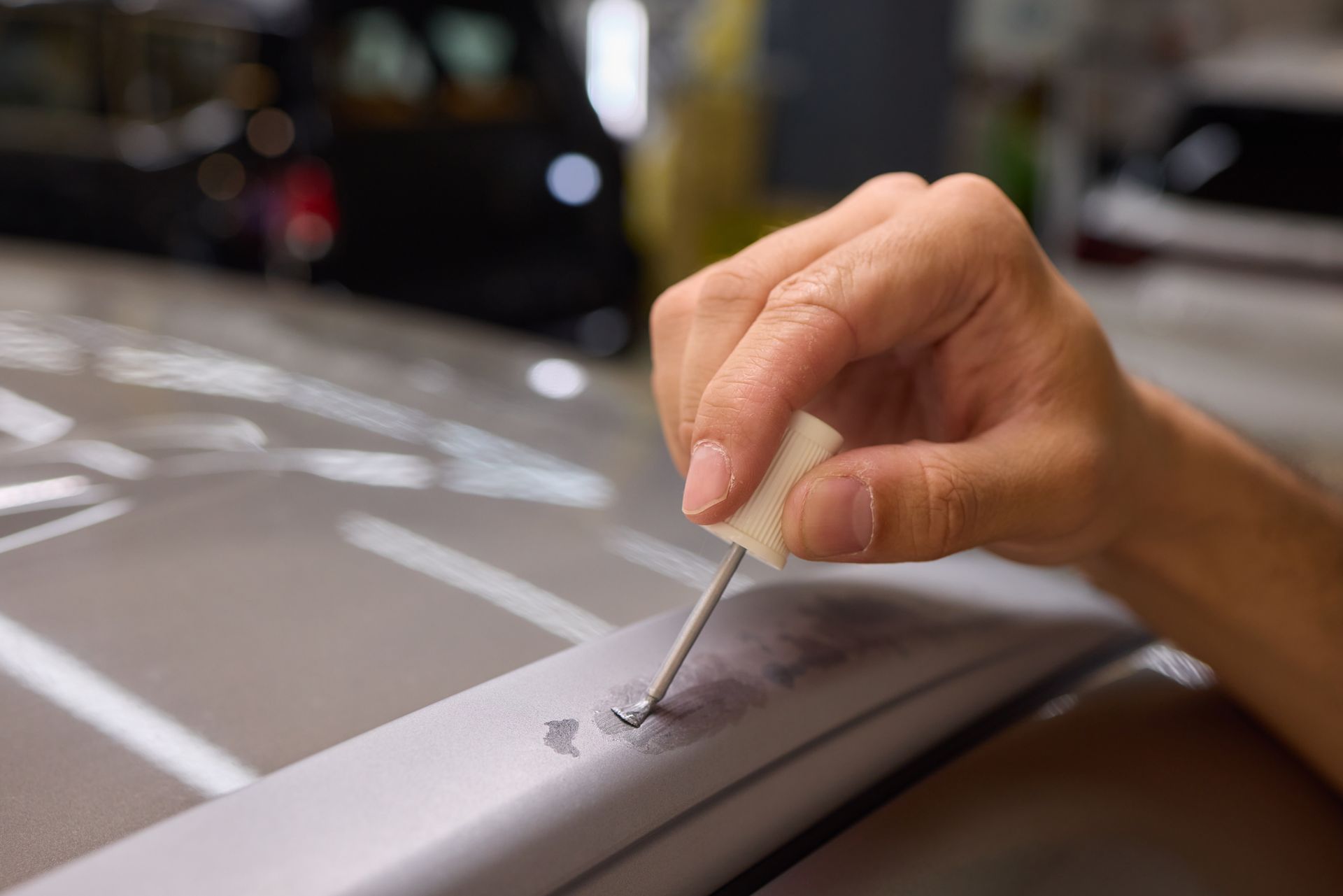 A man is painting a scratch on the side of a car.