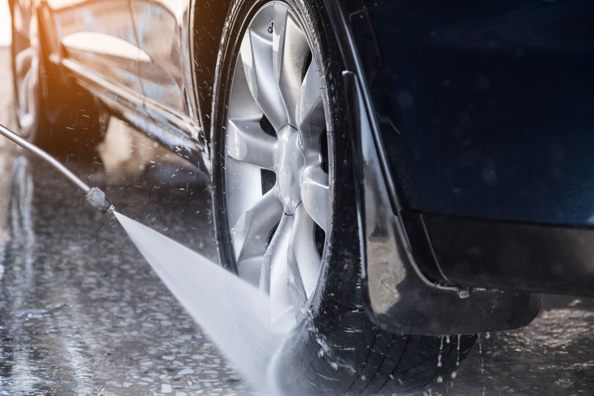 A car is being washed with a high pressure washer.