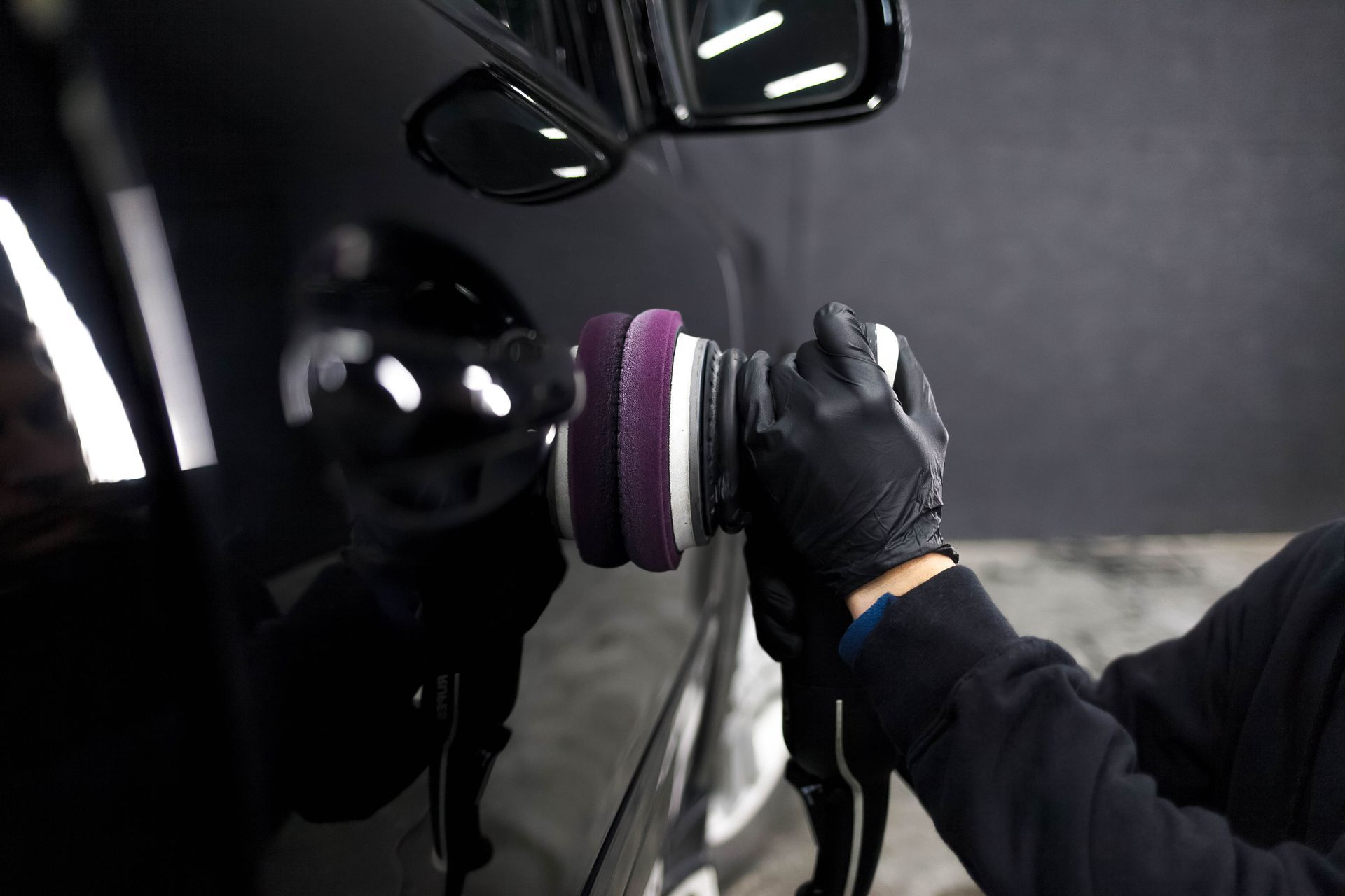 A car is being washed with a high pressure washer.