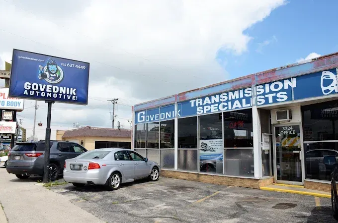 Auto repair shop exterior with “Transmission Specialists” sign and parked cars