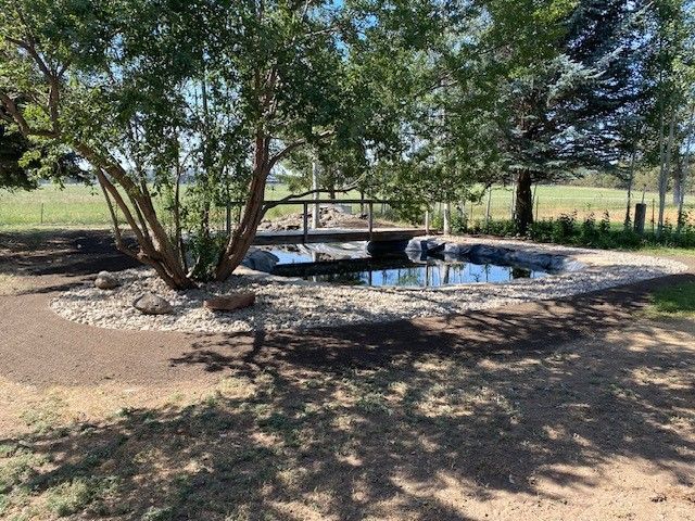 A pond with a bridge over it and trees in the background.