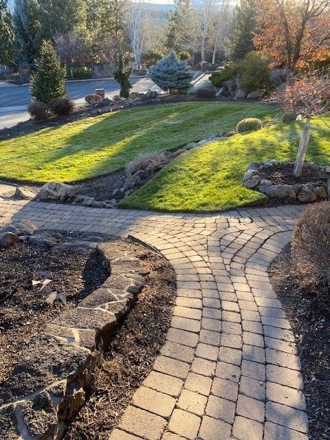 A brick walkway leading to a lush green lawn
