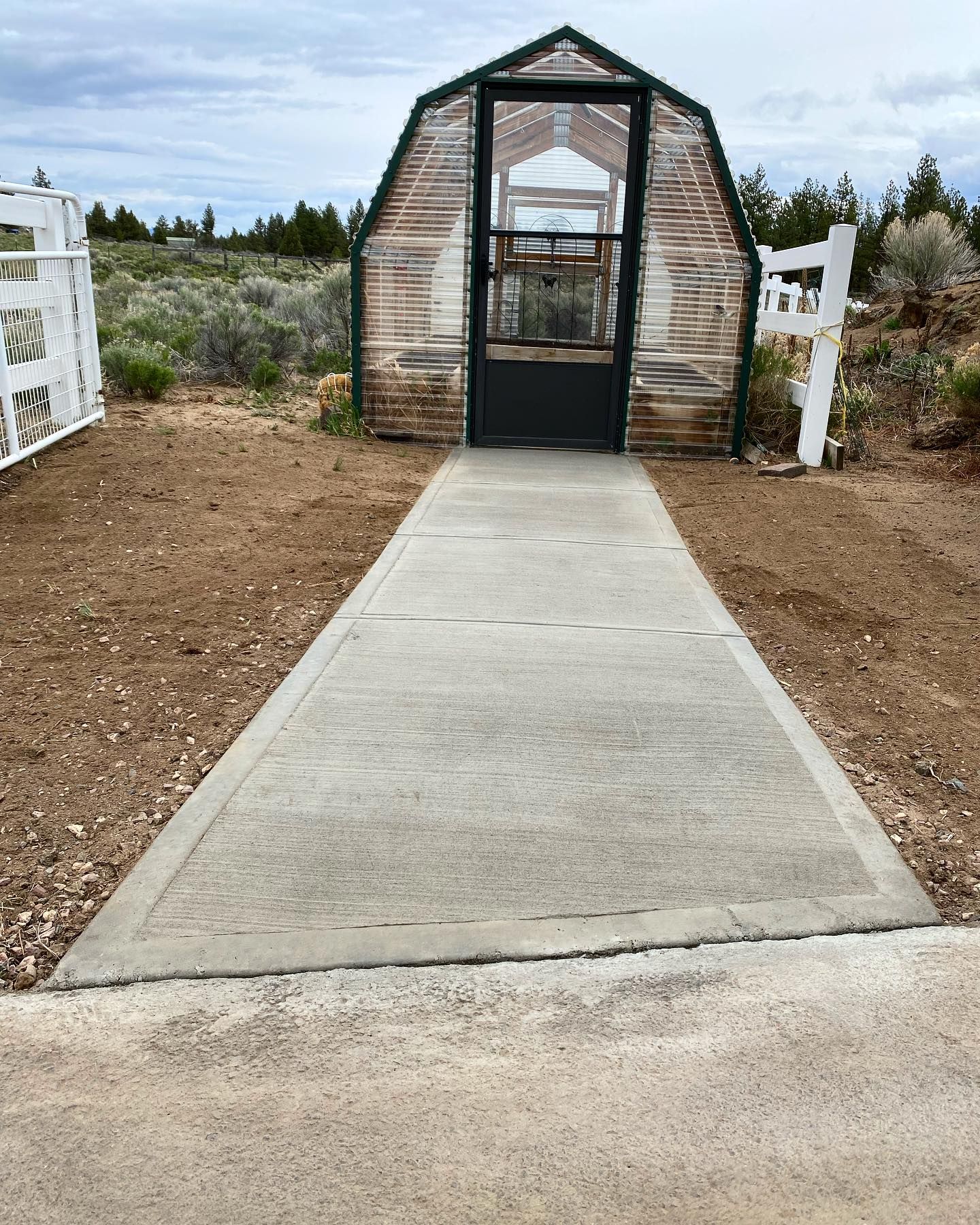 A greenhouse with a concrete walkway leading to it