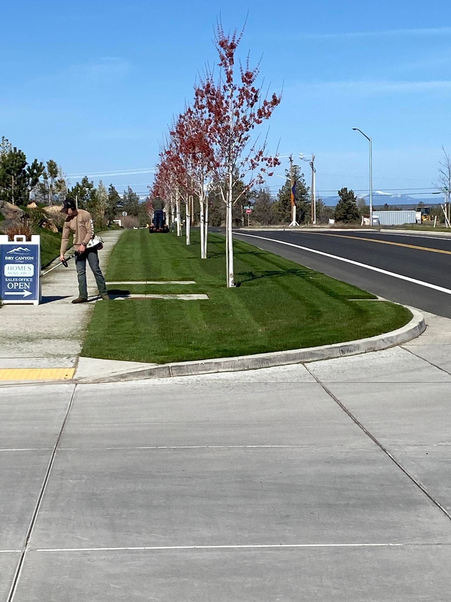 A man is mowing the grass on the side of the road.