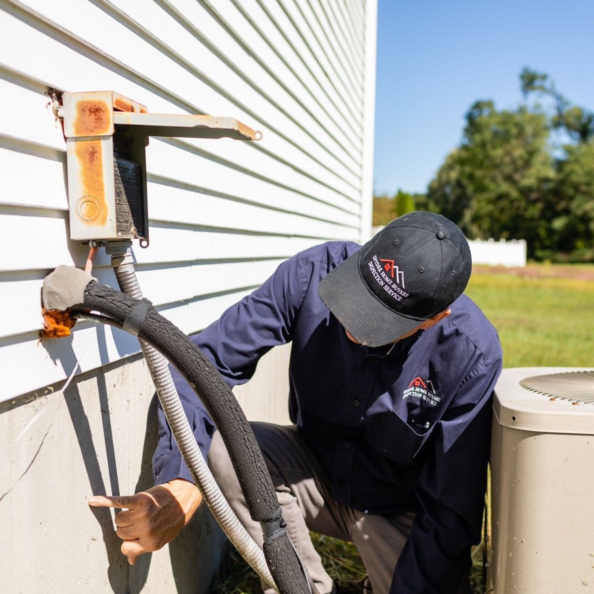 HVAC technician inspecting outdoor air conditioner, beside a house on a sunny day.