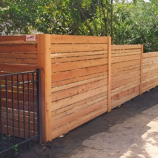 Fence With A Metal Gate Is Surrounded By Trees — Warren, MI — Kimberly Fence & Supply