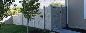Gray stone fence with a matching gate, green grass, and a small tree.
