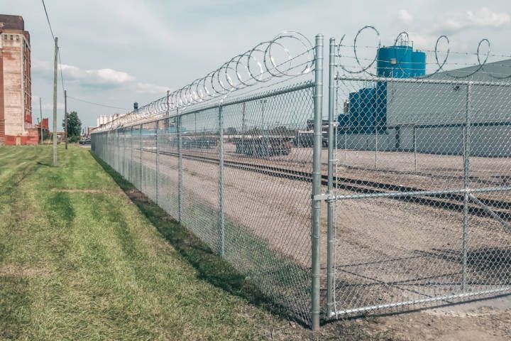 Chain Link Fence With Barbed Wire Surrounding A Train Yard — Warren, MI — Kimberly Fence & Supply