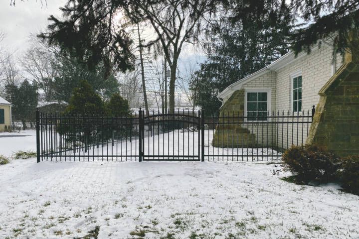 A Snowy Yard With A Fence And A House — Warren, MI — Kimberly Fence & Supply
