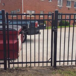 Black Metal Fence With A Truck Parked Behind It — Warren, MI — Kimberly Fence & Supply