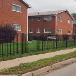 Brick Apartment Building With A Metal Fence Around It — Warren, MI — Kimberly Fence & Supply