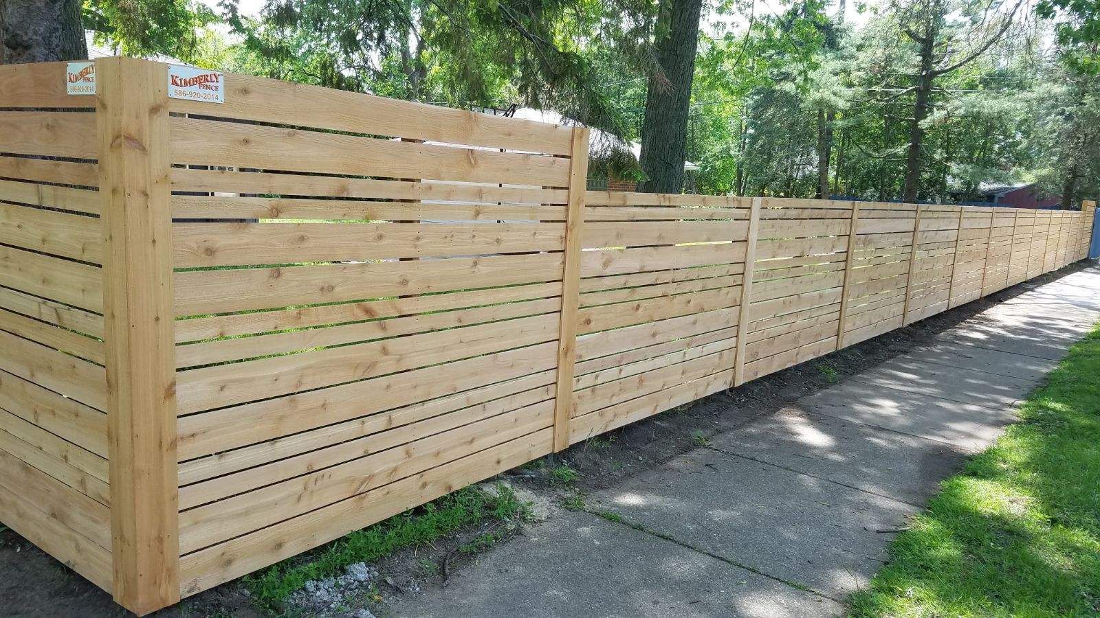 Wooden horizontal slat fence along a sidewalk.