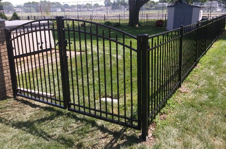 Black metal fence with gate in a grassy yard.