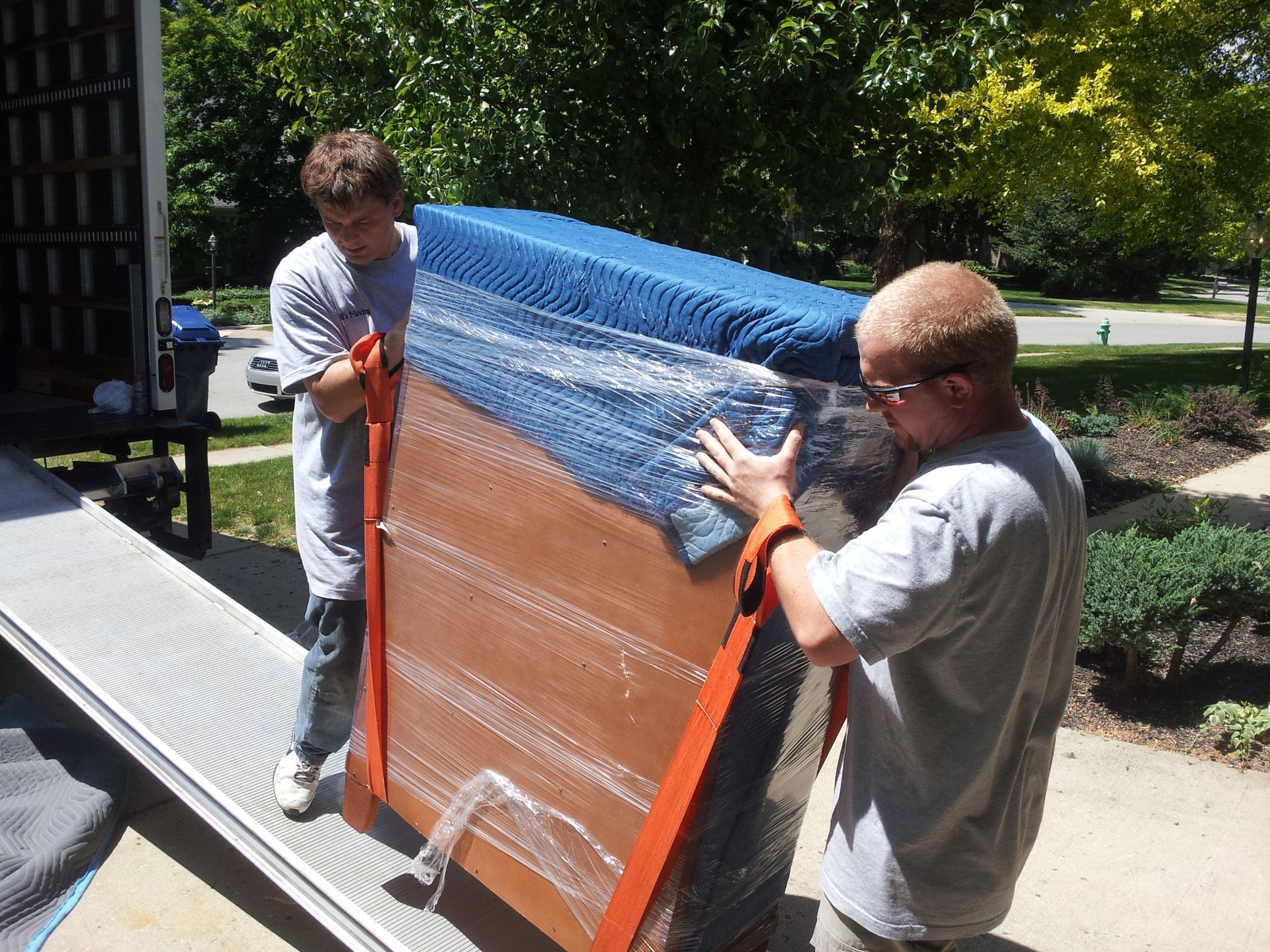 Two men are carrying a large piece of furniture