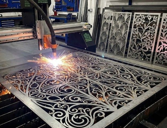 CNC plasma cutting machine creating intricate decorative metal art pattern in Nottingham workshop