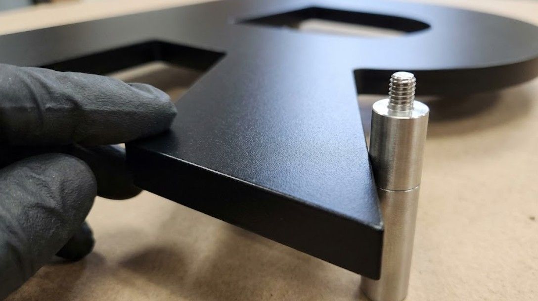 Close-up detail showing quality finish and mounting hardware of custom metal business signage