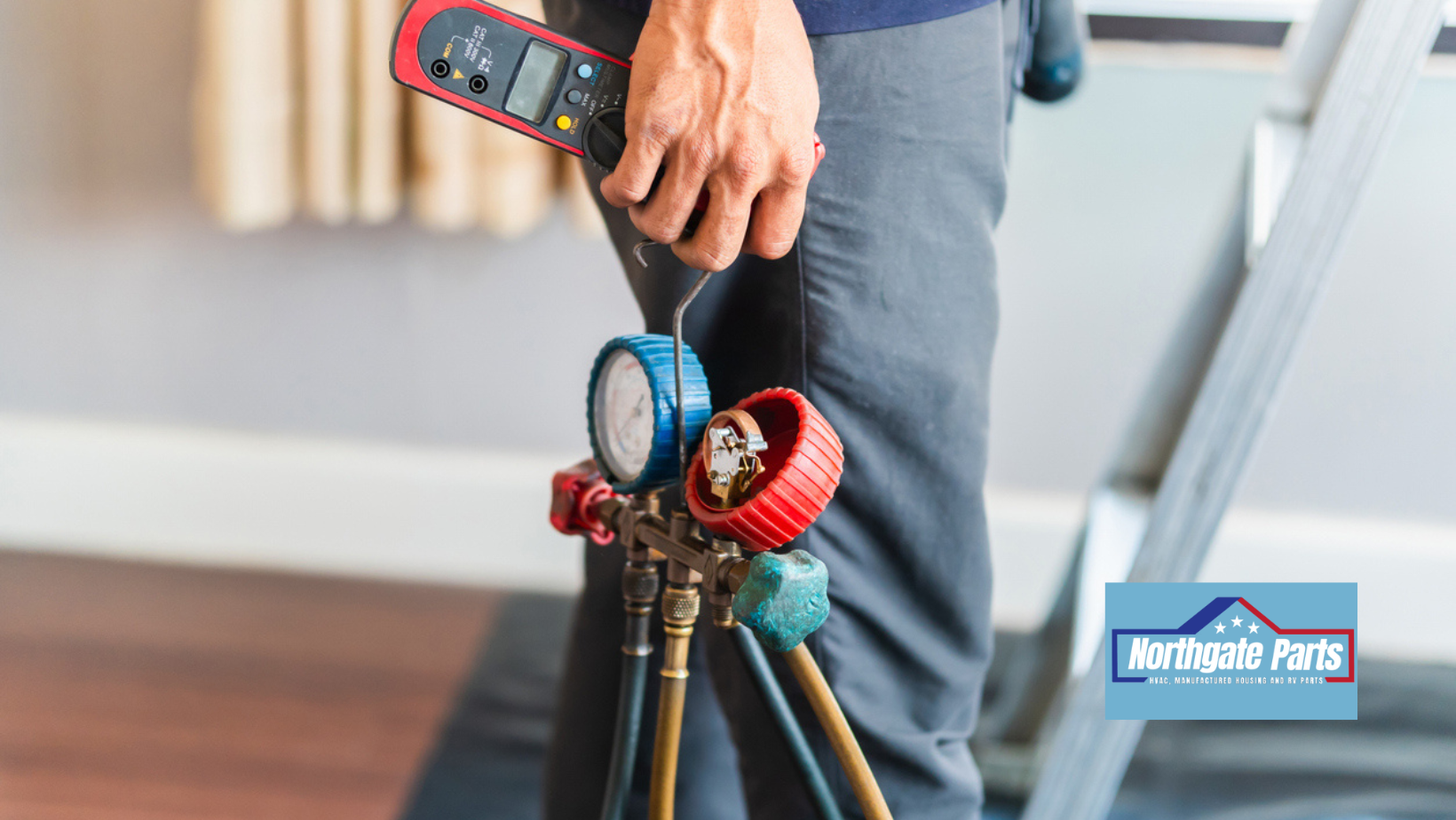 HVAC technician holding gauges and a digital meter, near a ladder indoors.