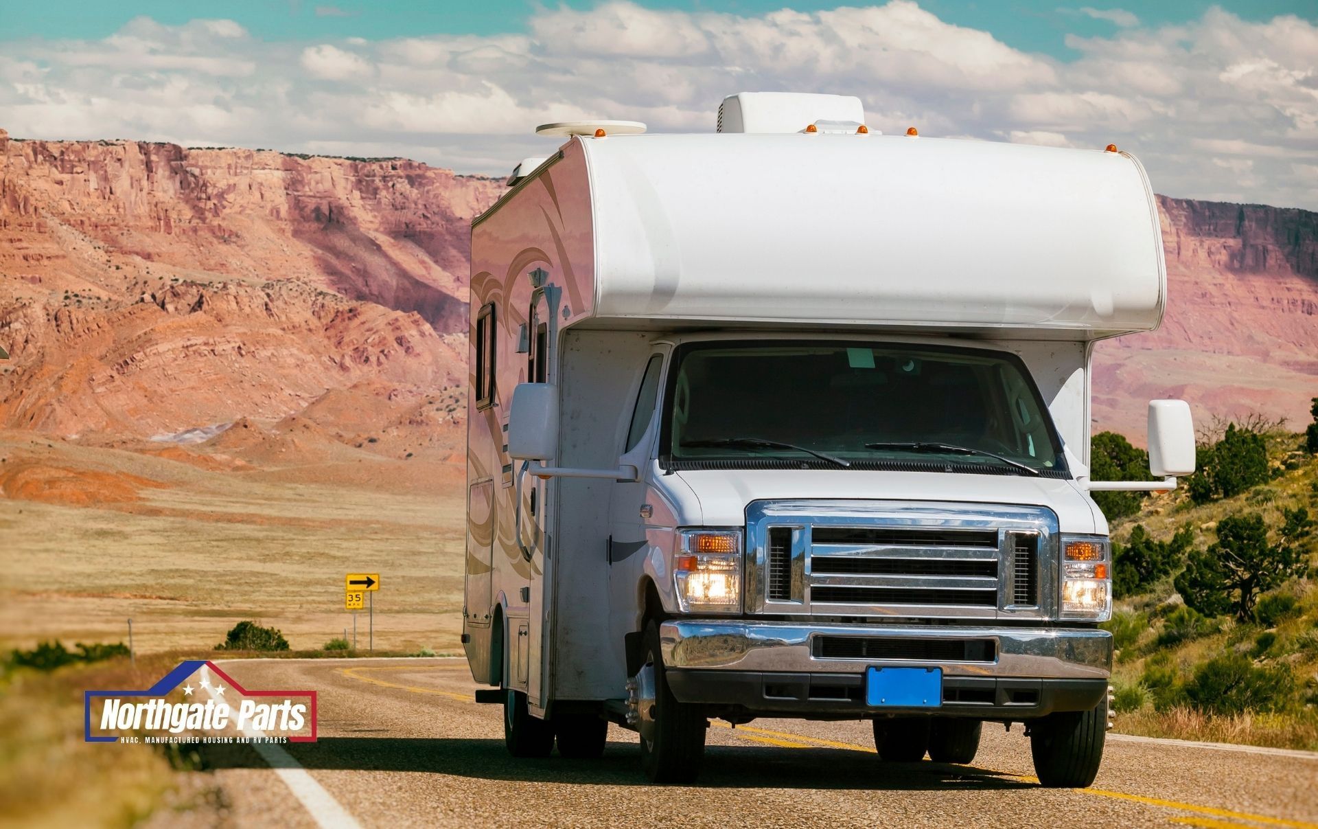 A rv is driving down a road with mountains in the background.