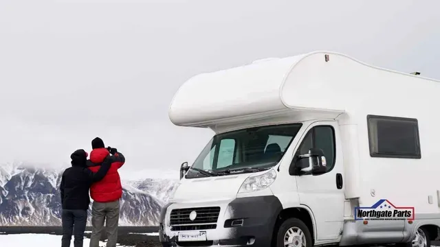 A couple standing next to a white rv in the snow.