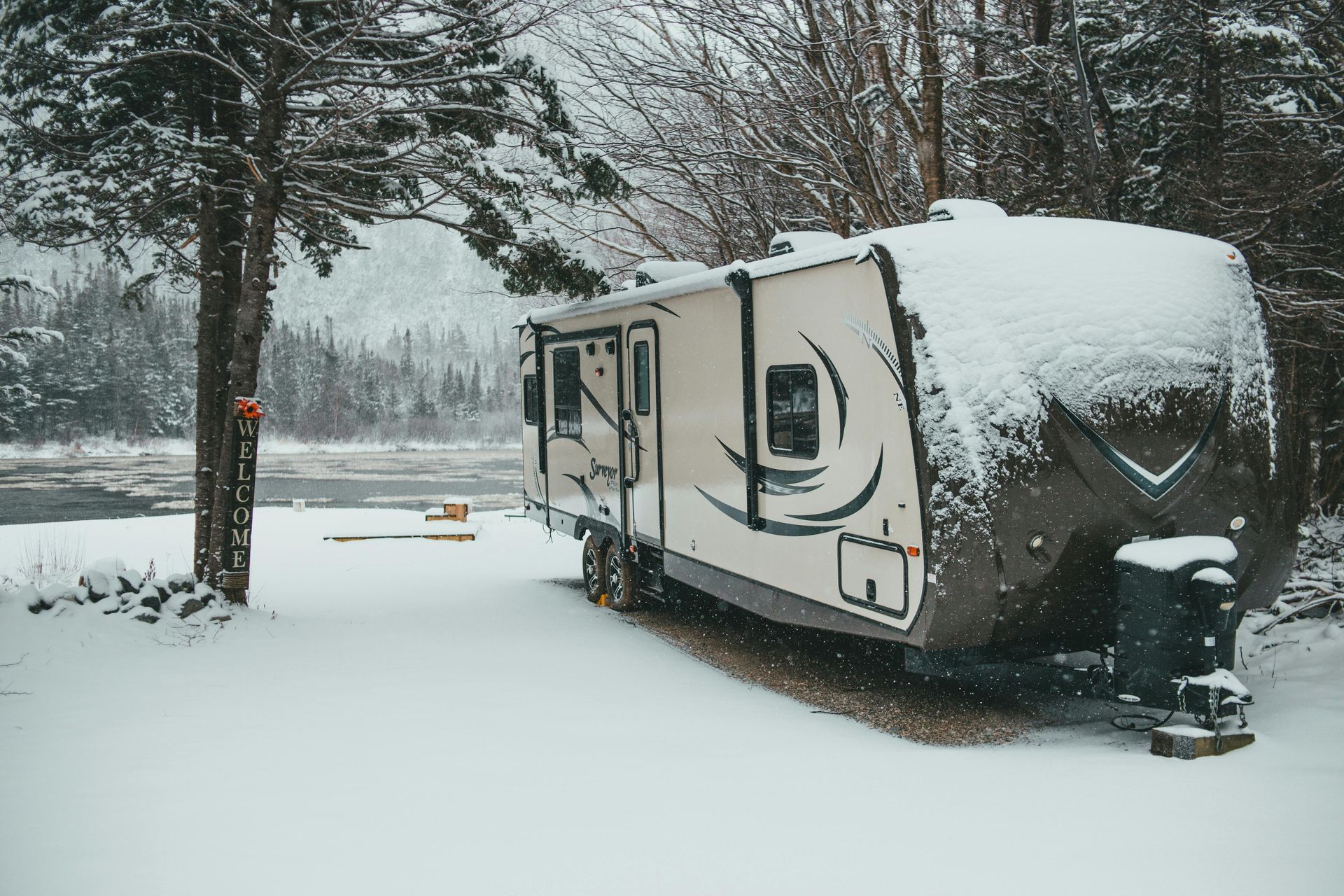 People by a white RV in a snowy landscape, one person taking a photo.