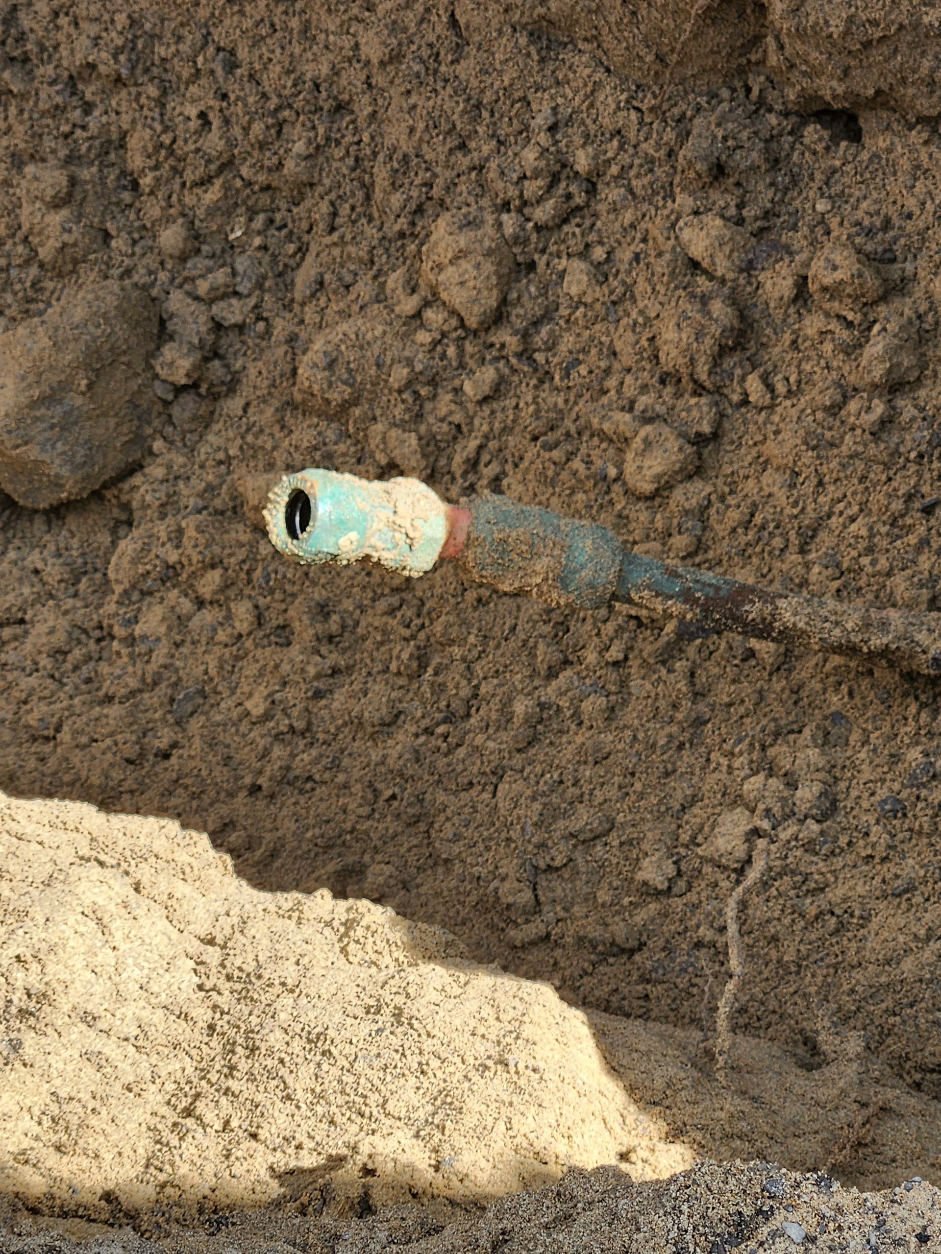 Un tuyau est posé dans la terre à côté d'un tas de terre.