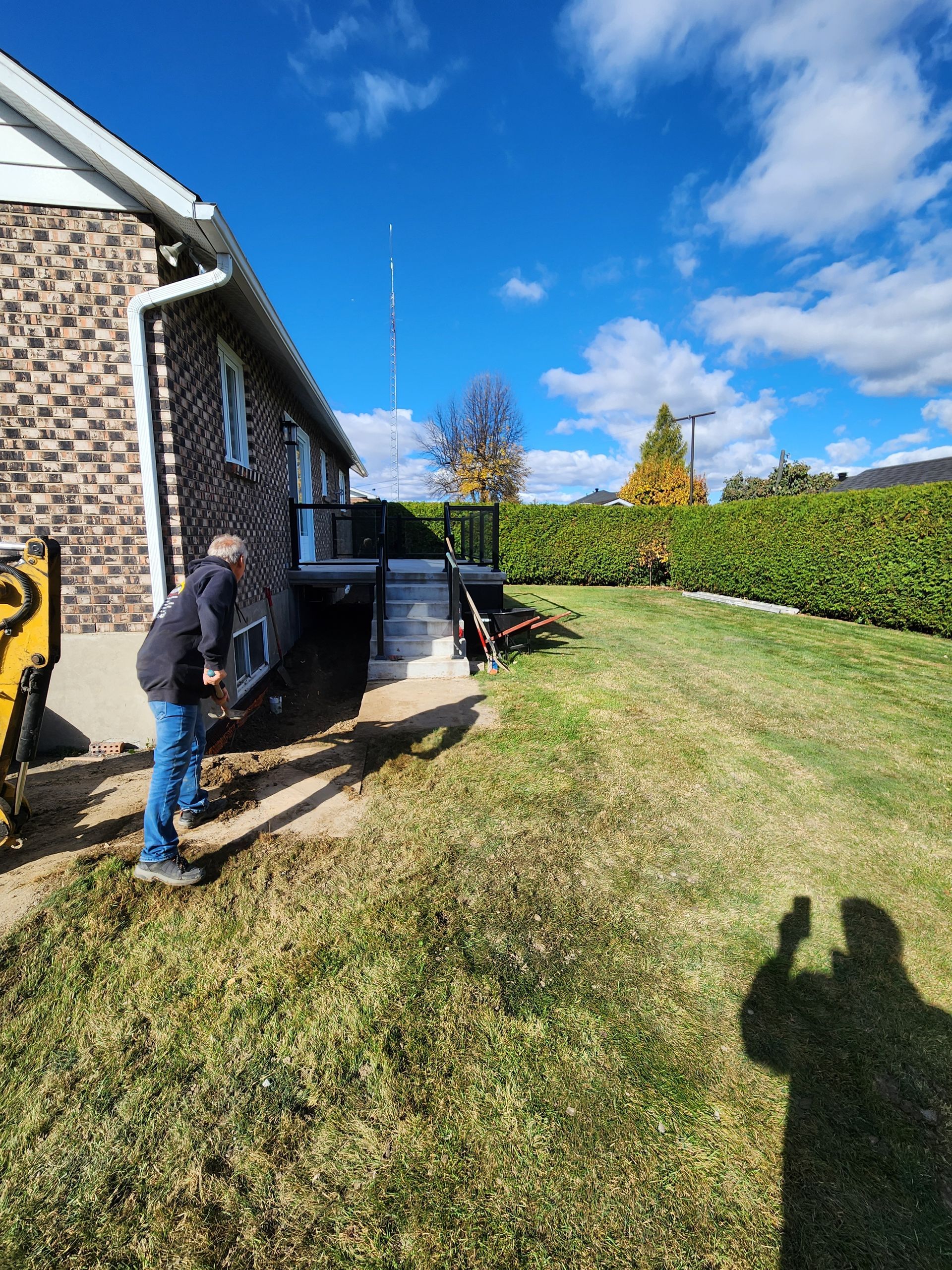 Un homme se tient debout dans l'herbe devant une maison.