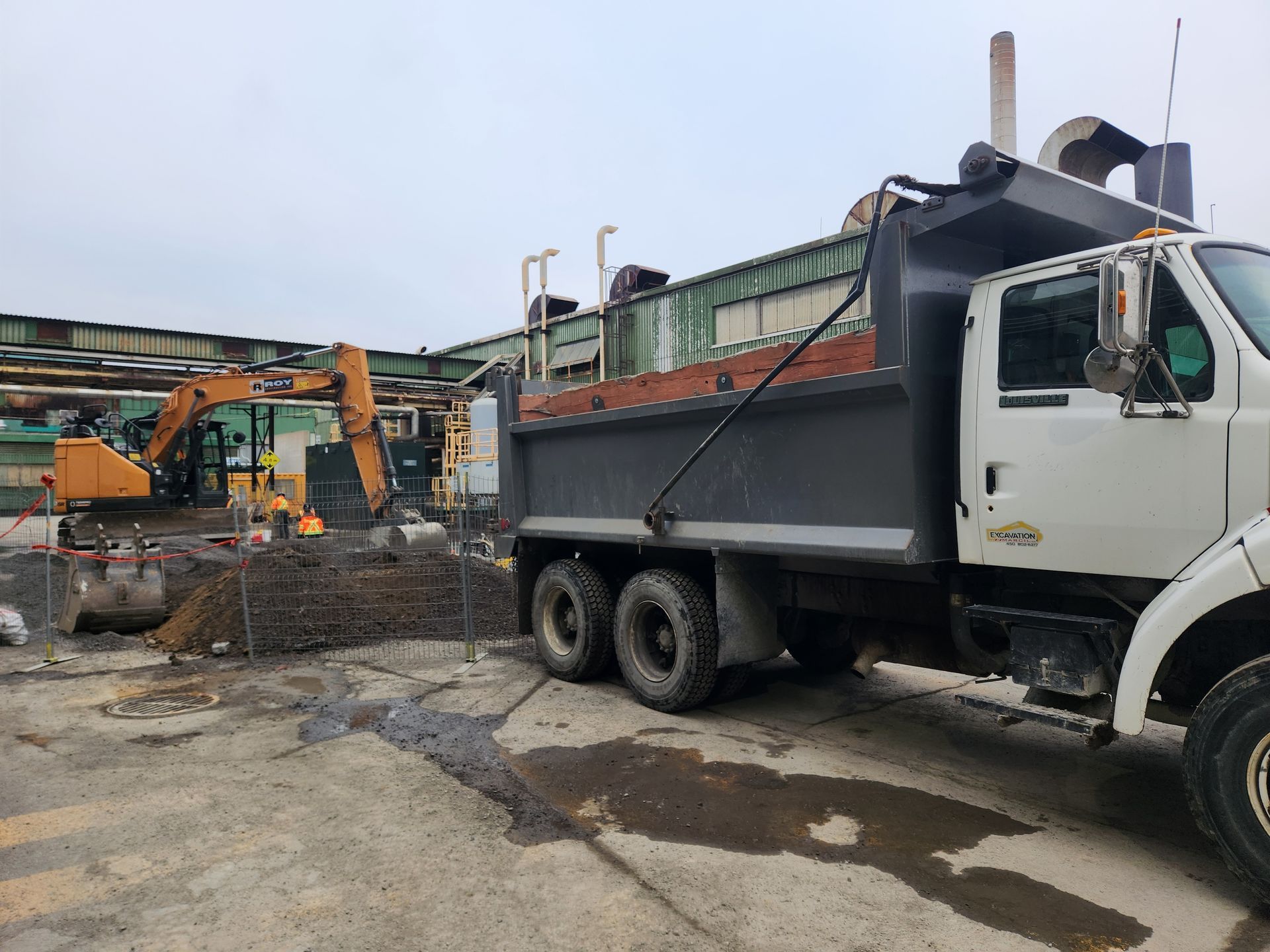 Un camion à benne basculante est garé devant un chantier de construction.