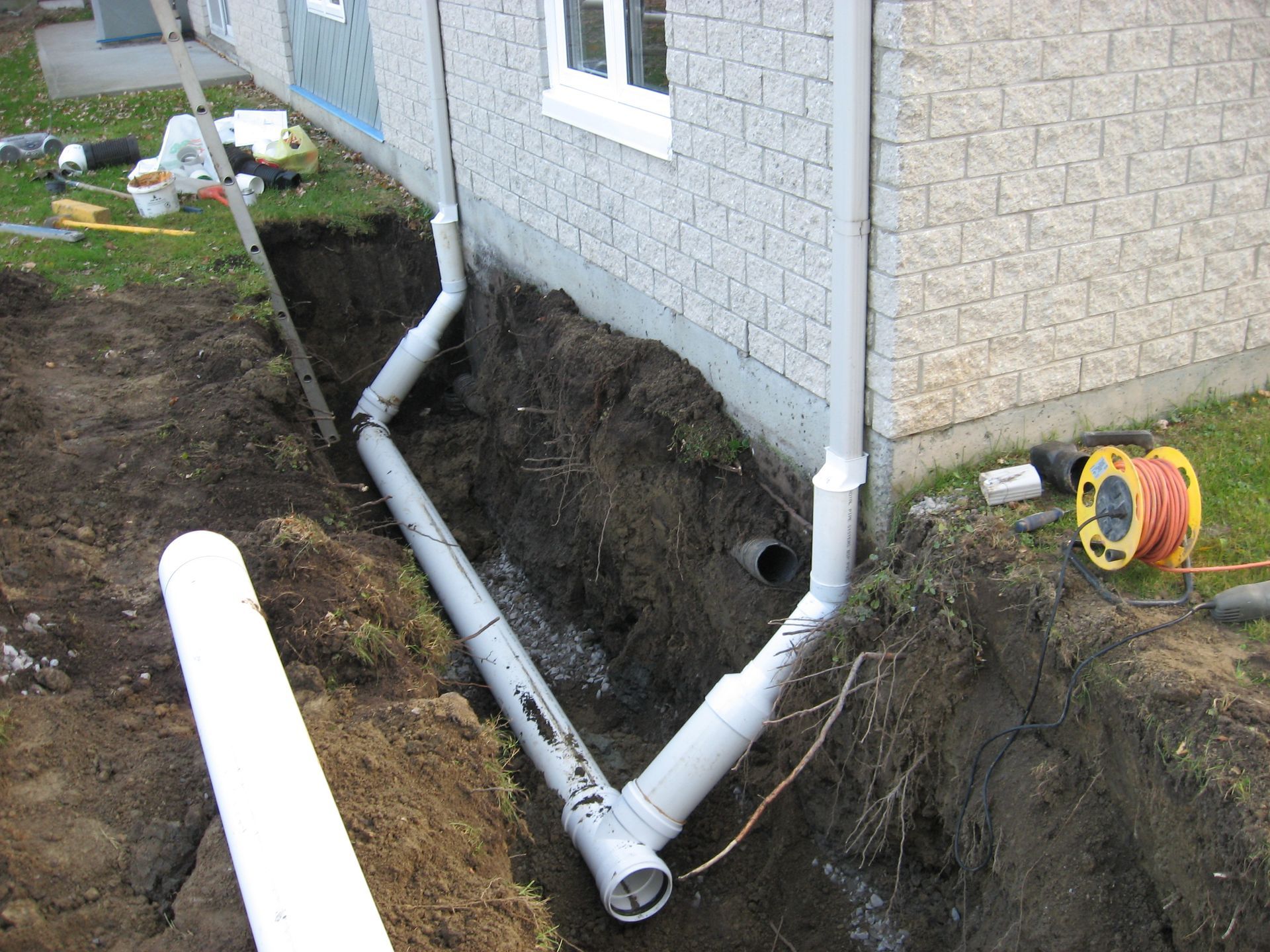 Un tuyau d'évacuation est en cours d'installation sur le côté d'une maison.