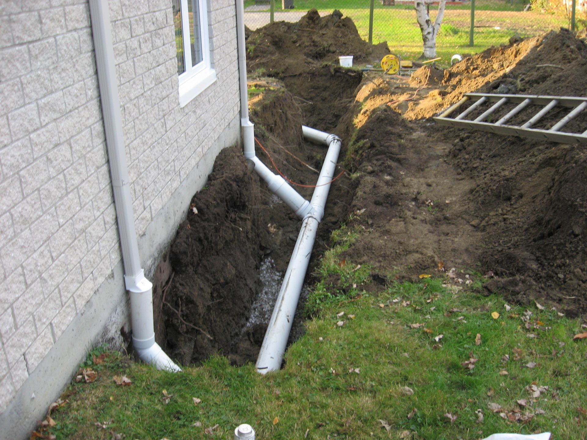 Un tuyau d'évacuation est en cours d'installation sur le côté d'une maison