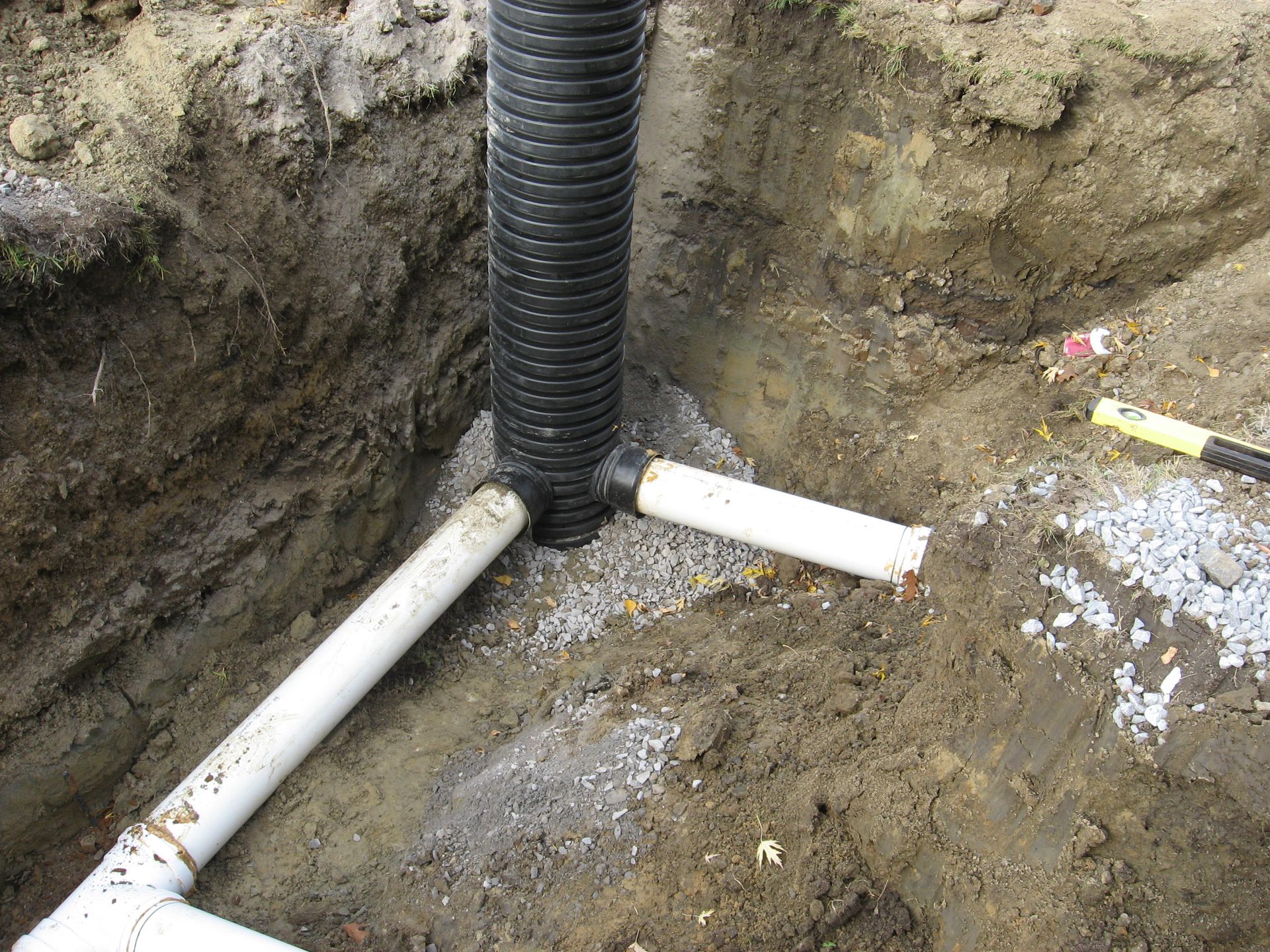 Un tuyau de drainage est en train d'être installé dans un trou dans le sol.