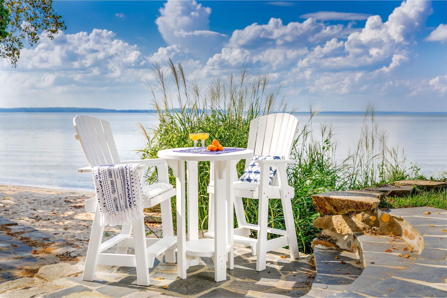 A table and chairs are sitting on a patio next to a body of water.