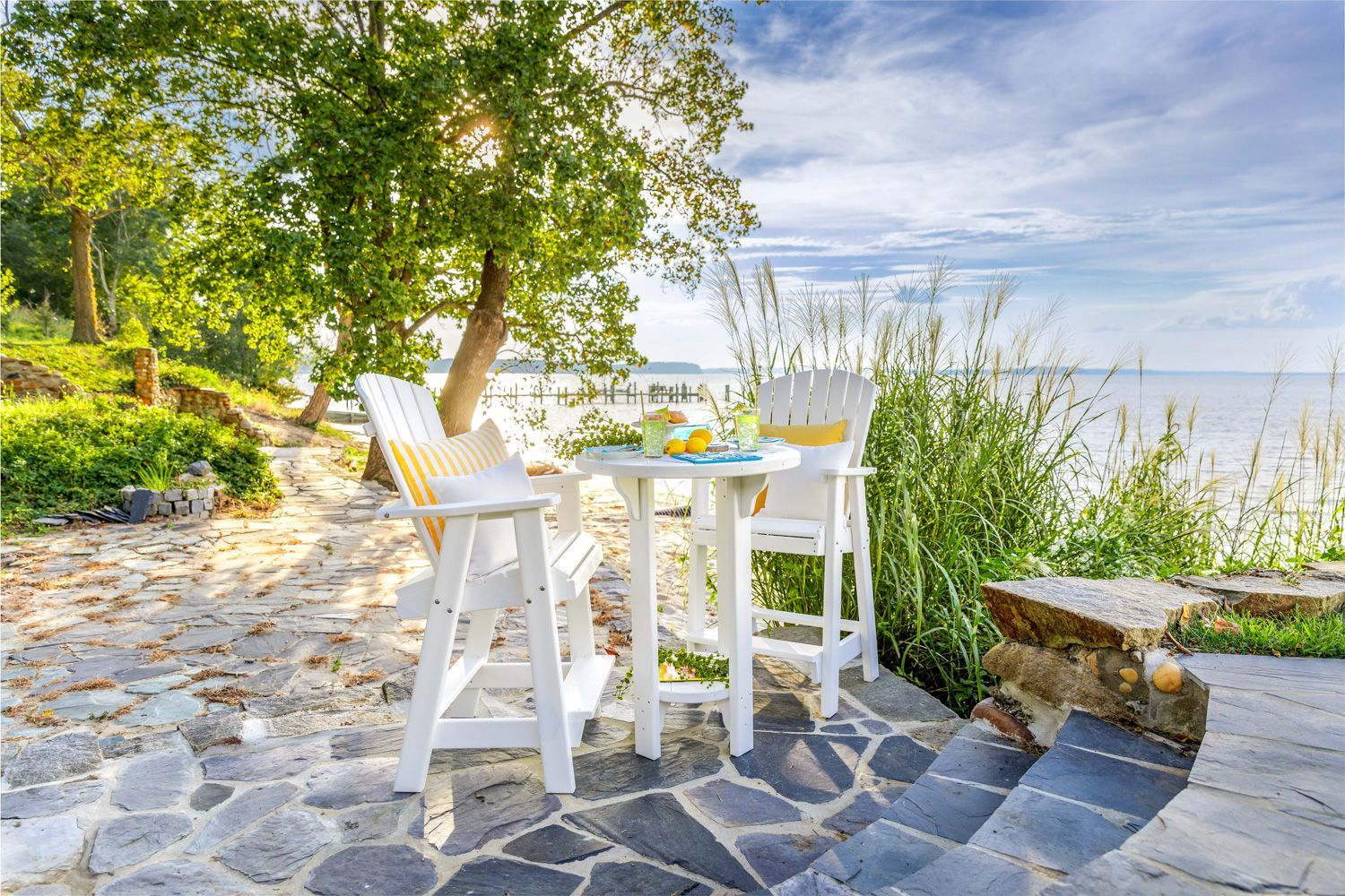 A patio with a table and chairs next to a body of water.