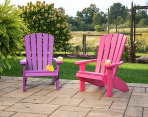 Two purple and pink adirondack chairs are sitting on a patio.