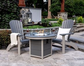Two chairs are sitting next to a fire pit on a patio.