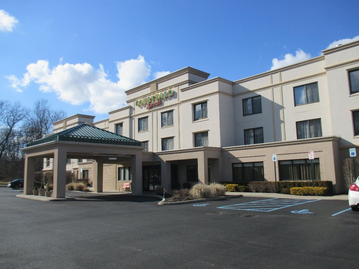 Three buckets of paint and brushes are sitting on a white towel in an empty room.