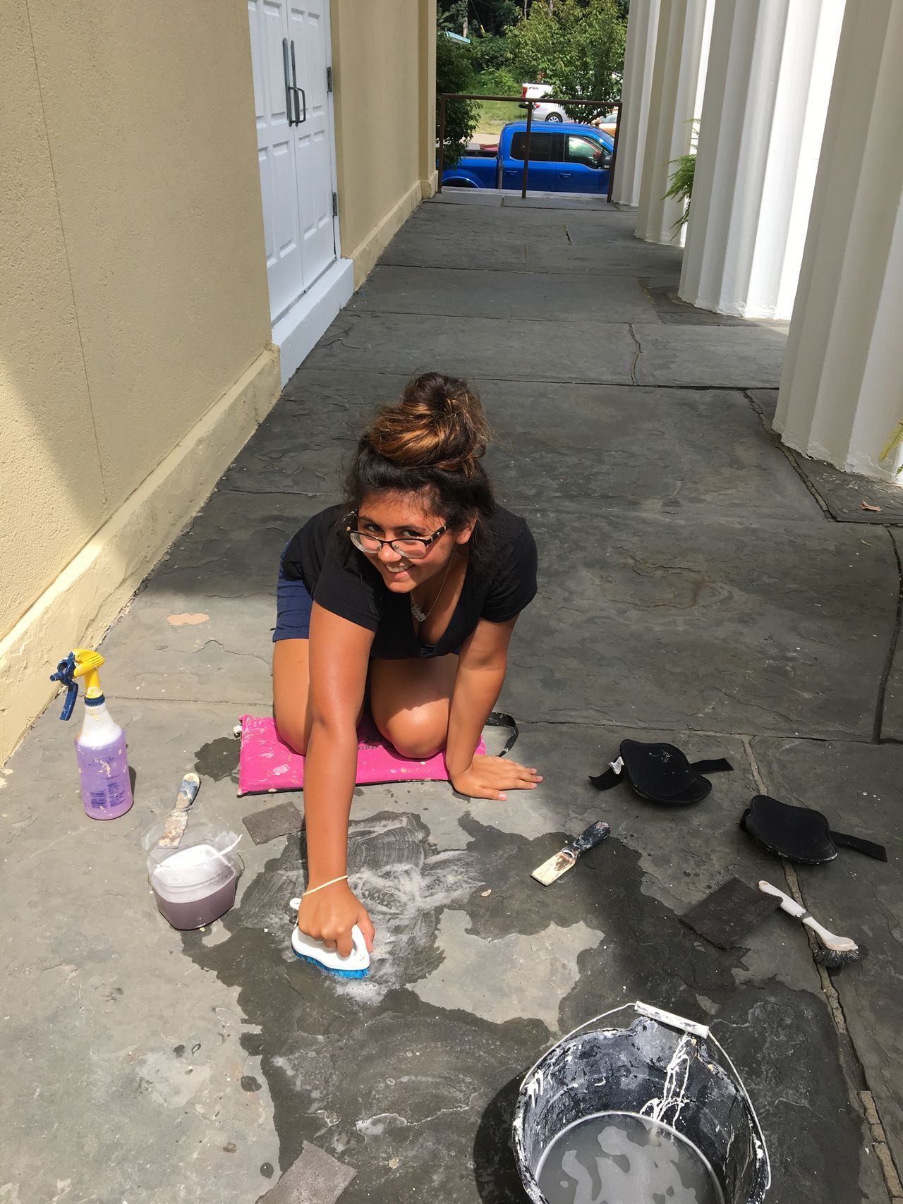 A woman is kneeling on the ground cleaning the floor with a sponge