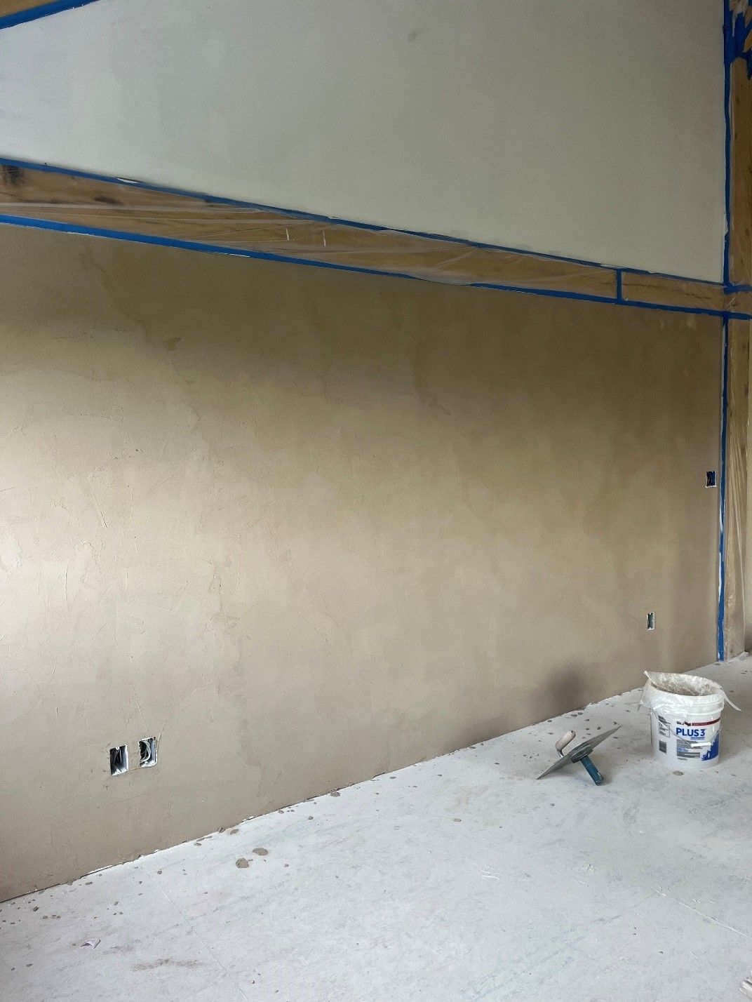 A bucket of paint sits on the floor in front of a wall