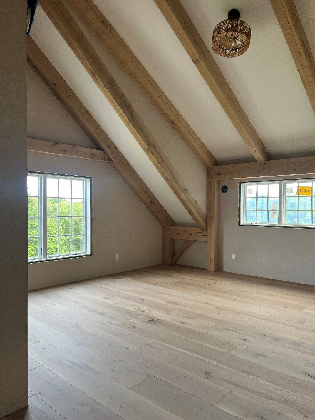 An empty room with wooden beams and windows
