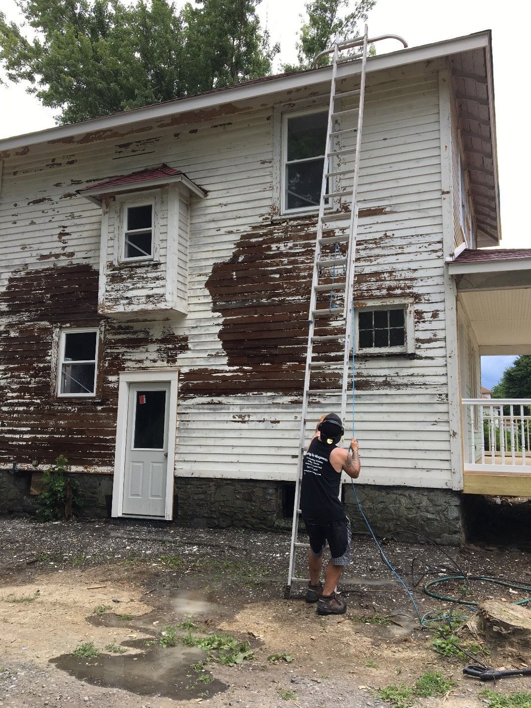 A man is standing on a ladder in front of a white house.