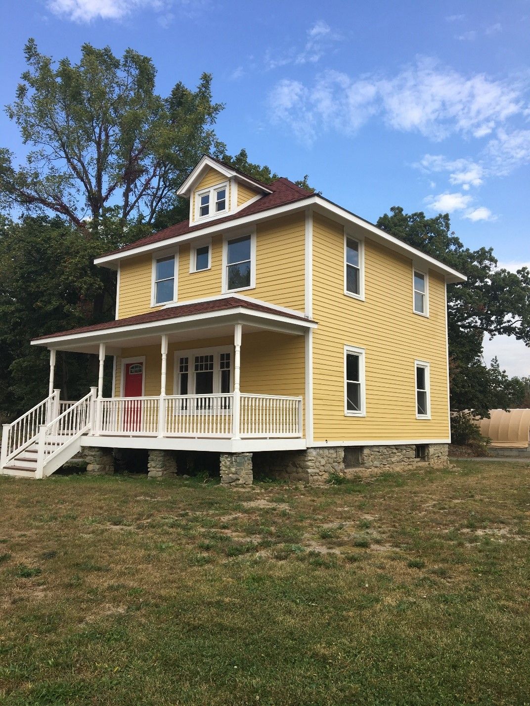 A yellow house with a white porch and stairs