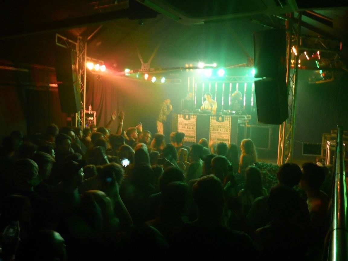 Crowded nightclub with colorful stage lights and performers on stage