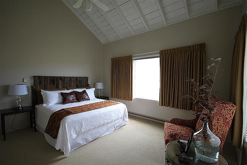 A bedroom with a bed , chair , table and window.