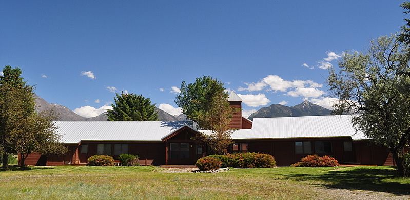 A large house with a white roof and mountains in the background