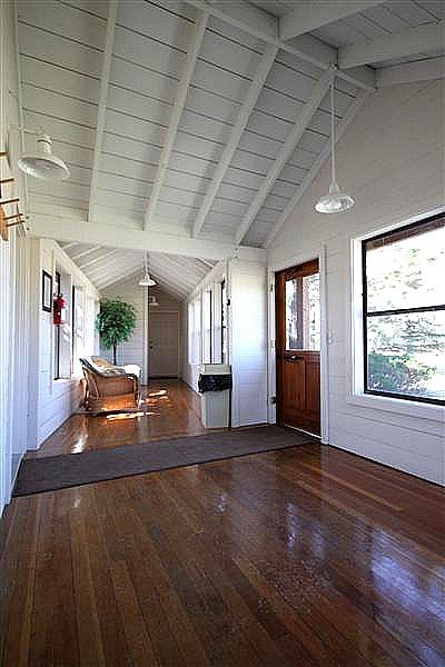 A long hallway with hardwood floors and a vaulted ceiling in a house.