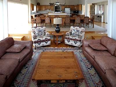 A living room with two couches , two chairs , a coffee table and a rug.