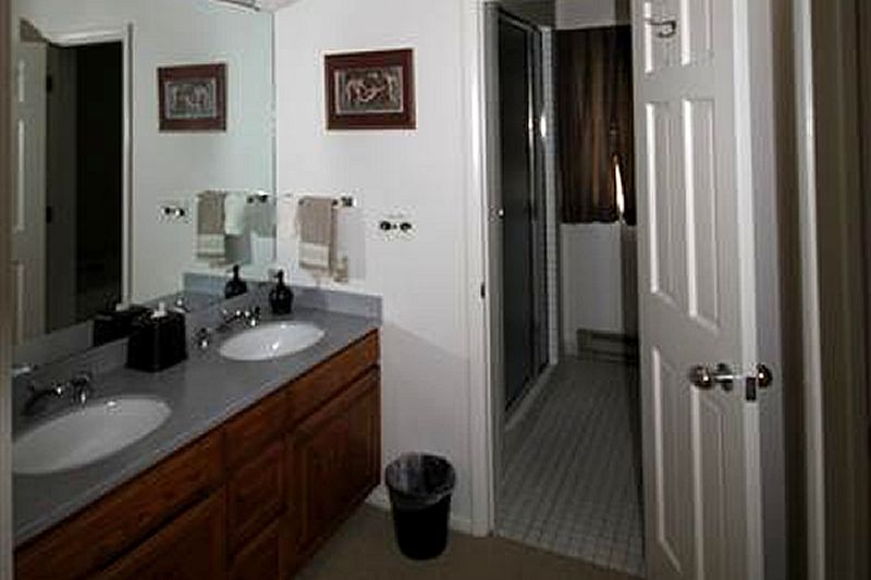 A bathroom with two sinks , a mirror and a trash can.