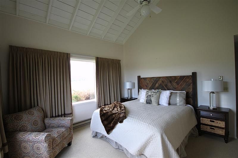 A bedroom with a large bed and a chair