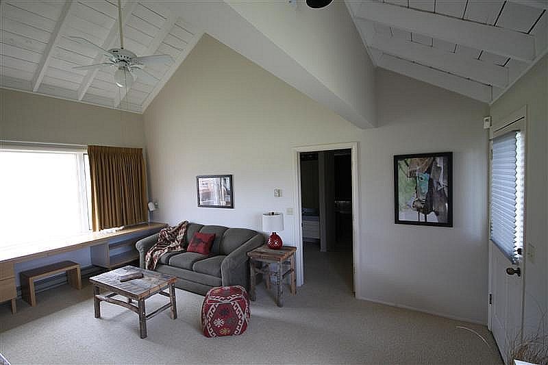 A living room with a couch , table , chairs and a ceiling fan.