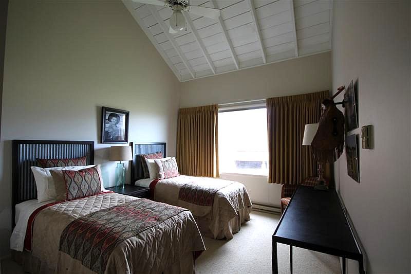 A bedroom with two twin beds and a ceiling fan.