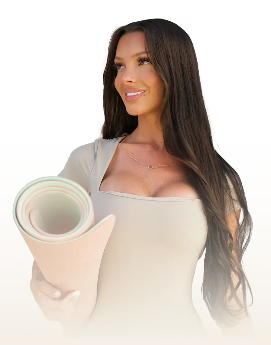 A woman is holding a yoga mat in her hands and smiling.